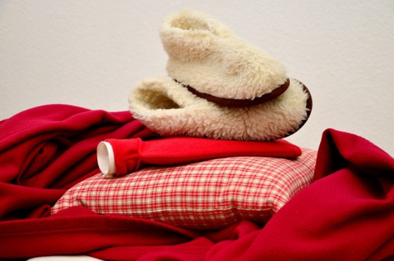 赤色の毛布と枕と湯たんぽが重なっている